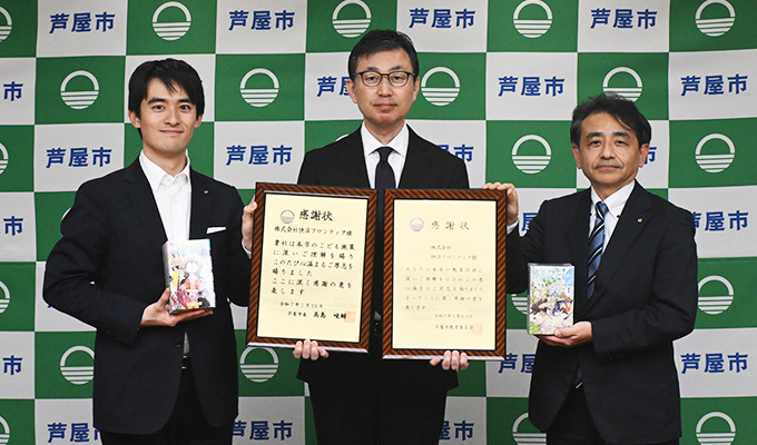 2025年1月、芦屋市役所で行われた漫画本の寄贈式の様子。左から、芦屋市の髙島崚輔市長、株式会社快活フロンティアの中川和幸取締役執行役員、芦屋市教育委員会の野村大祐教育長。