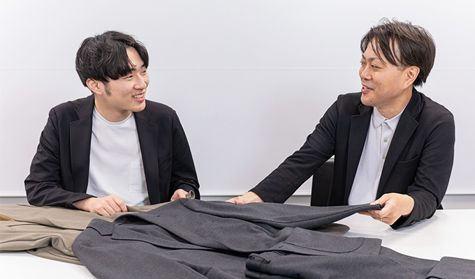 パジャマスーツ誕生の背景を説明する先輩・児島さん。興味深そうに耳を傾ける入社3年目の溝口さん